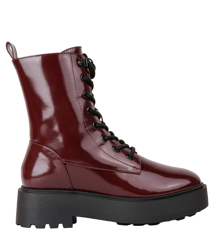 Shiny burgundy boot with black sole on a light gray background