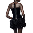 Back view of woman wearing a black nightclub bandage dress for women with lace-up corset and ruffled skirt