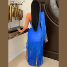 Woman wearing blue one shoulder fringe dress with long sleeves and slit standing indoors