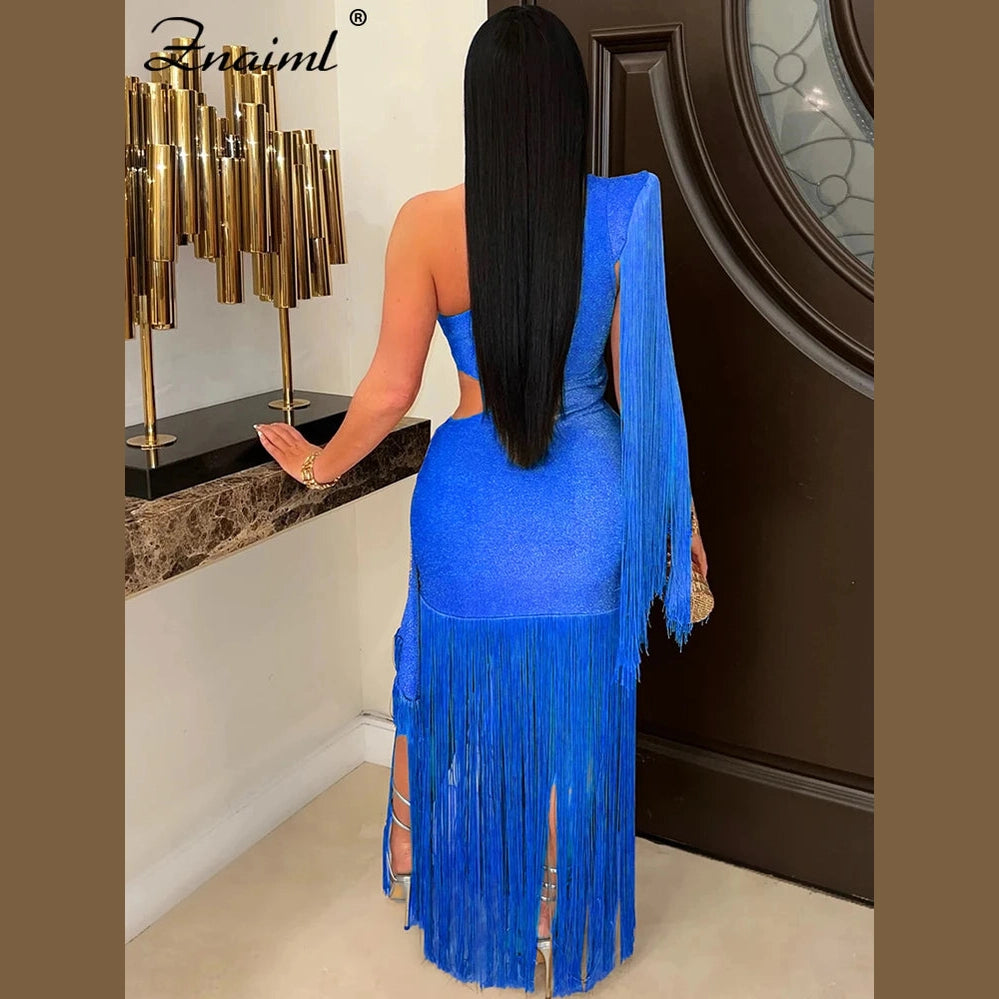Woman wearing blue one shoulder fringe dress with long sleeves and slit standing indoors
