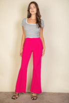 Woman wearing pink flare trousers for women paired with a striped short sleeve top and black sandals