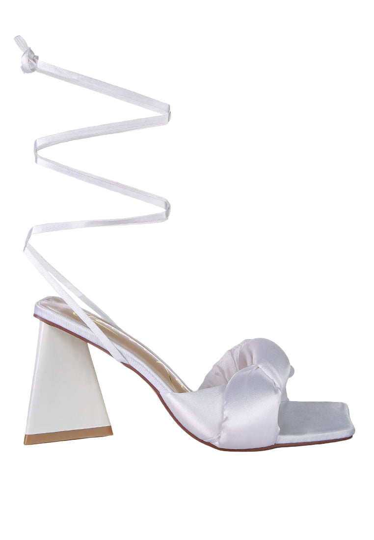White satin sandal with a unique heel design on a light green background