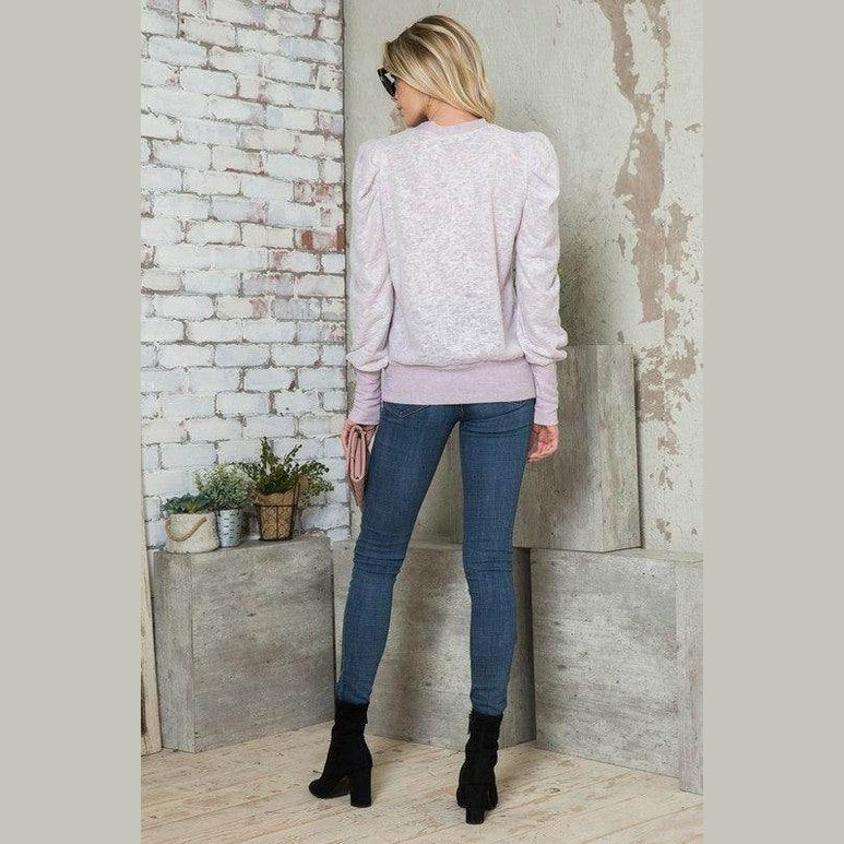 Back view of a light pink women's puff sleeve top for casual outings paired with blue jeans.