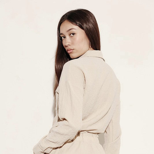 Woman wearing a beige relaxed fit button down shorts set by Miss Sparkling with long sleeves and shorts