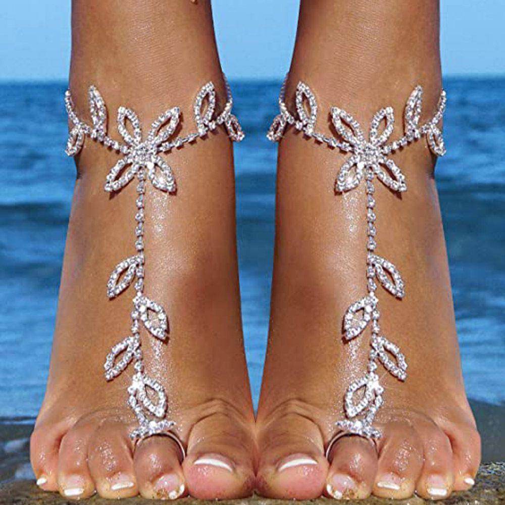 Elegant rhinestone toe ring jewelry with floral design on bare feet at the beach