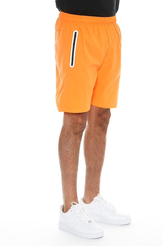WEIV men's bright orange running shorts with zip pocket worn with white sneakers