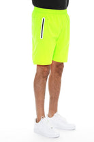 WEIV men's neon green running shorts with zip pocket and elastic waistband paired with white sneakers