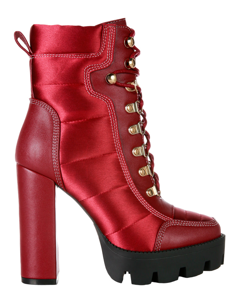 Red high-heeled platform boot with gold laces on a white background