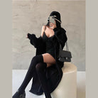 Woman wearing a sexy black club dress for women with black cardigan thigh-high stockings and a black purse