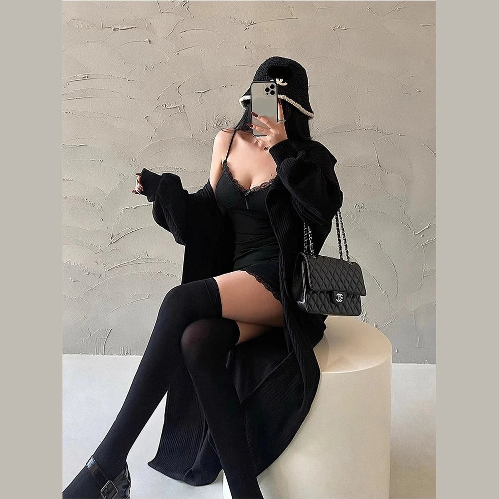 Woman wearing a sexy black club dress for women with black cardigan thigh-high stockings and a black purse