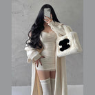 Woman wearing a sexy black club dress for women styled with long cardigan and fluffy white handbag