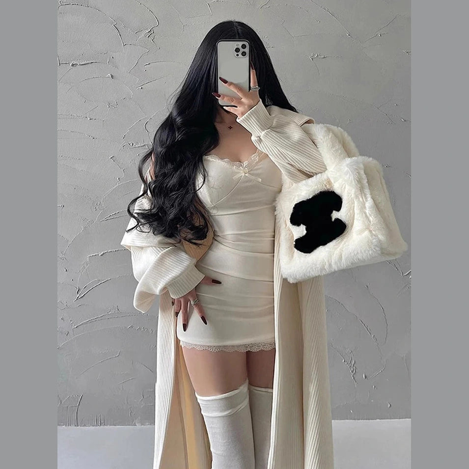 Woman wearing a sexy black club dress for women styled with long cardigan and fluffy white handbag