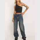 Woman wearing a black one-shoulder sexy vacation tops for women paired with relaxed fit jeans