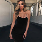 Woman wearing a black sleeveless party mini dress for women with thin straps in a modern indoor setting