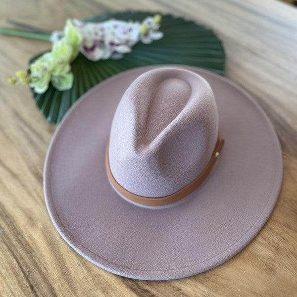 Stylish panama hat in light pink with a brown band on a wooden surface