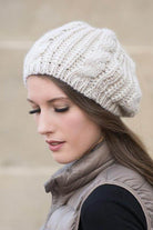 Woman wearing a cream stylish vacation beret with a cozy knit design for a trendy look