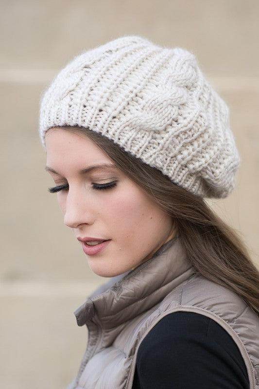 Woman wearing a cream stylish vacation beret with a cozy knit design for a trendy look