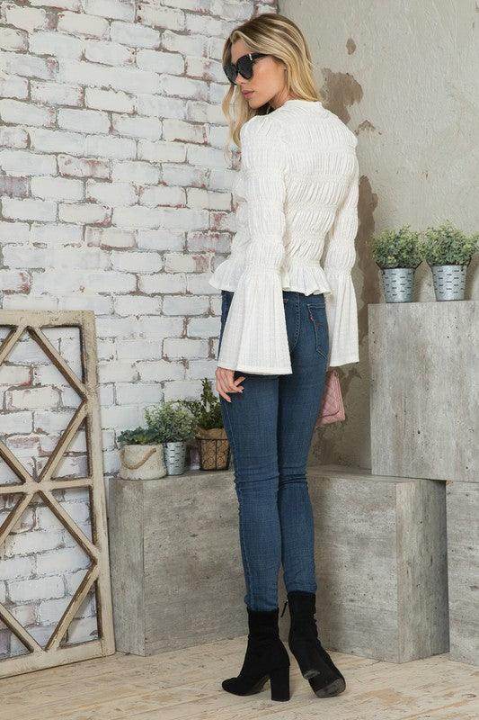 Women's stylish vacation blouse in white with bell sleeves paired with skinny jeans and ankle boots