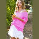 La Miel thin Taylor sweater in vibrant pink paired with a white dress for a stylish look