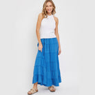 Woman wearing a blue tiered maxi skirt for women with a white sleeveless top and sandals