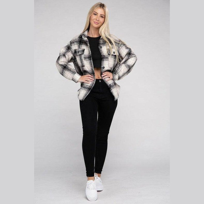Stylish woman wearing a trendy plaid shacket jacket over a black crop top and black jeans