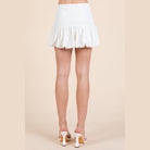 VacationGrabs white trendy summer mini skirts with ruffled hem worn with white heels