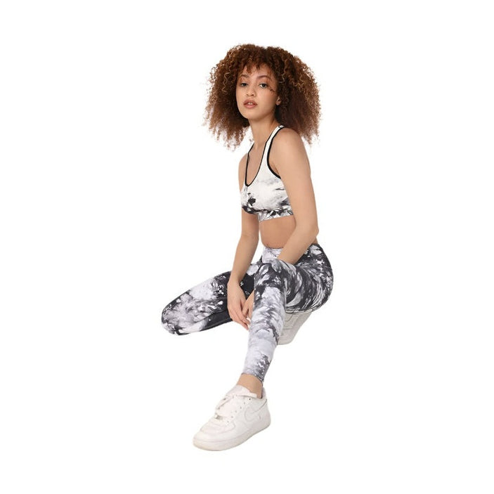 Woman wearing black and white tye dye sports bra and matching leggings with white sneakers