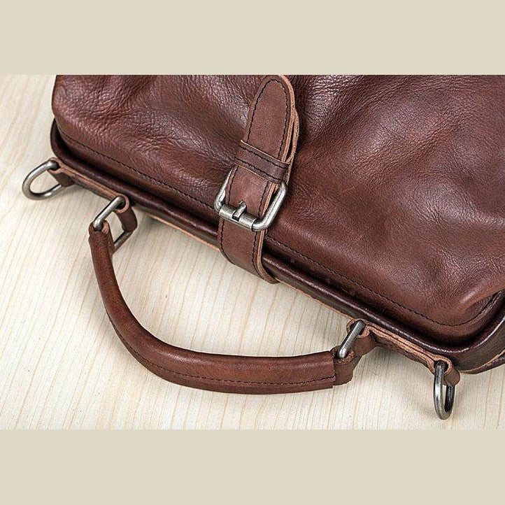 Brown leather unisex shoulder bag for travel with durable handle and metal accents