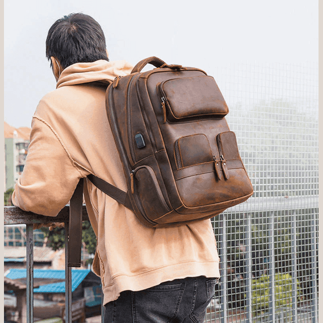 Urban leather weekender backpack worn by a man, featuring multiple pockets for travel convenience