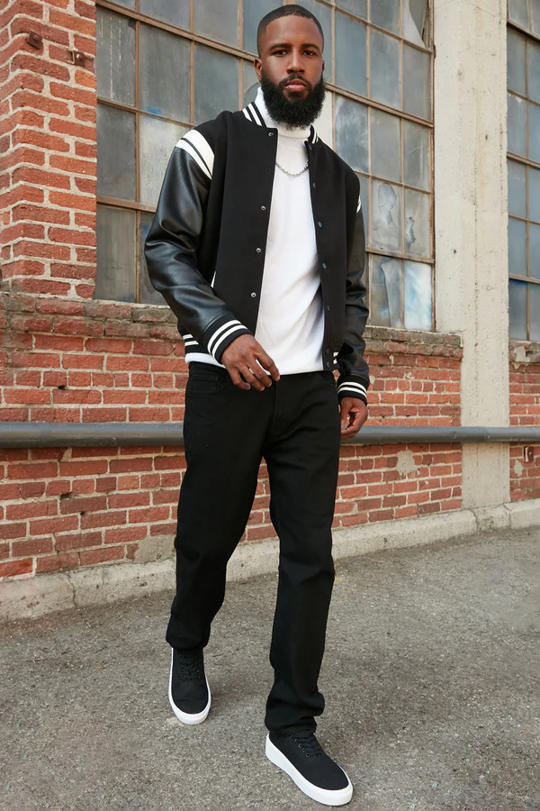 Man wearing VacationGrabs urban style jeans for men paired with a black varsity jacket and sneakers