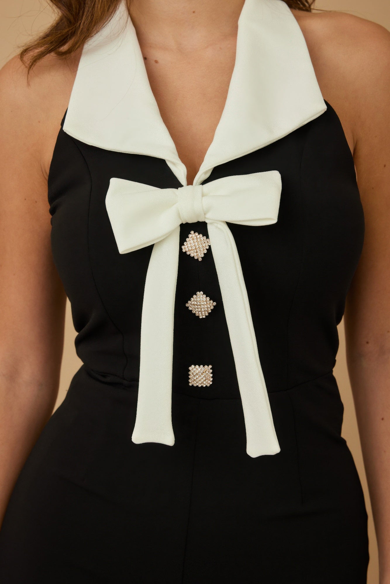 Elegant vacation jumpsuit outfit for women with a bow tie and decorative buttons in black and white