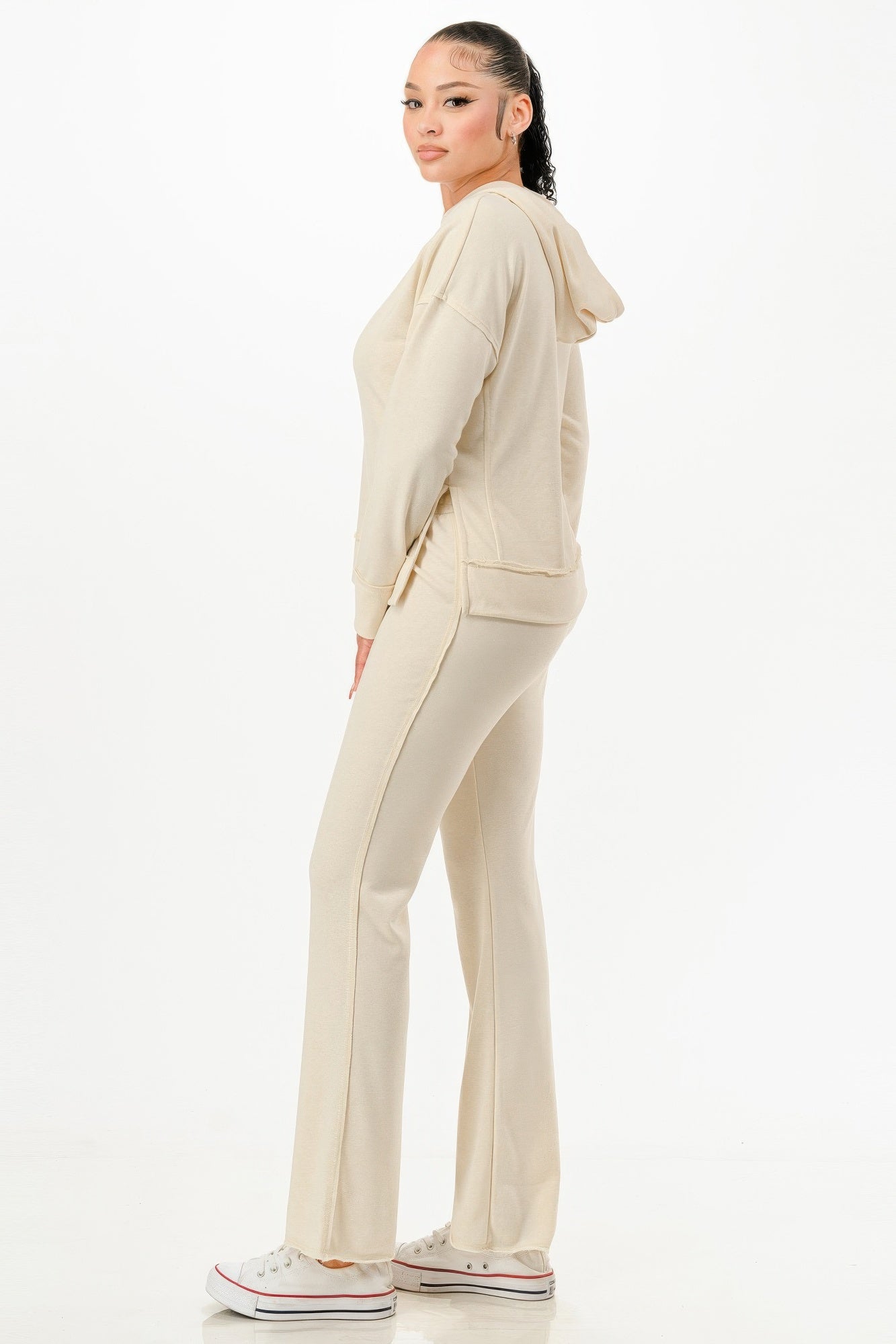 Woman wearing beige vacation loungewear set with hoodie and matching pants paired with white sneakers