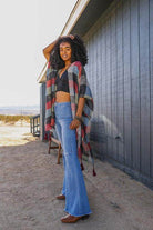 Stylish woman wearing a vacation style kimono over a black top and flared jeans outdoors