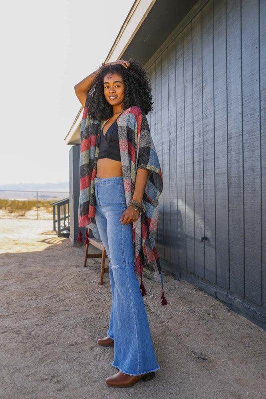 Stylish woman wearing a vacation style kimono over a black top and flared jeans outdoors