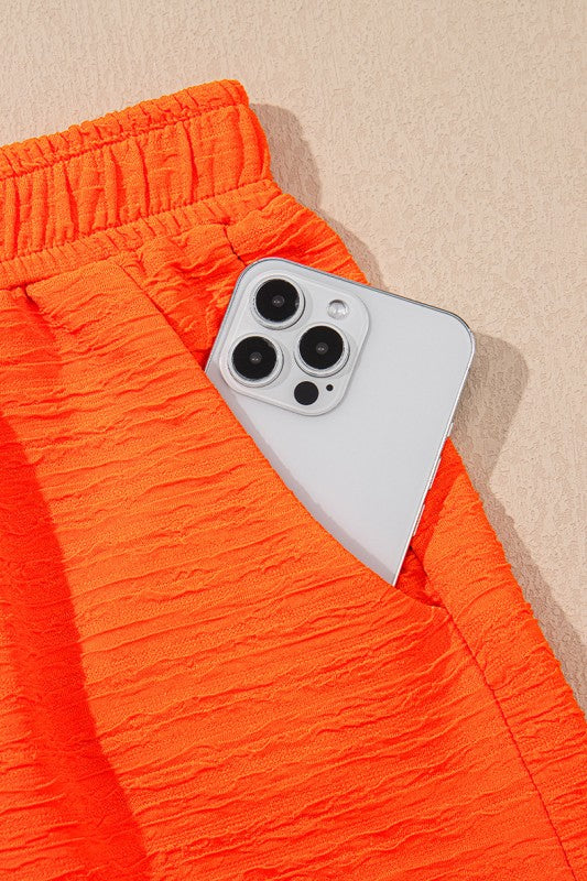 Close-up of bright orange textured pants pocket with white smartphone for casual vacation outfit for women