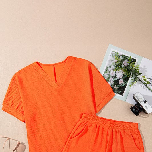 YNIQUE bright orange casual vacation outfit for women with V-neck top and elastic waist shorts