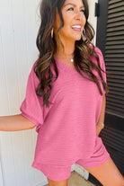 Woman wearing a pink relaxed top and shorts casual vacation outfit for women by YNIQUE smiling outdoors