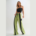 Woman wearing comfortable wide leg lounge trousers in green with black side stripes by VacationGrabs