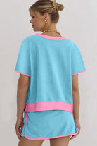Woman wearing YNIQUE drop shoulder casual summer set in light blue with pink trim, shown from the back