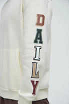 Men's cream hustle daily hoodie for vacation with colorful block letters printed on sleeve