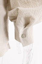 Close-up of sleeve cuff with button on beige relaxed fit button down shorts set by Miss Sparkling