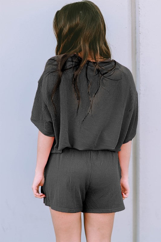 Back view of a woman wearing a black ribbed textured matching set for women with shorts and loose top