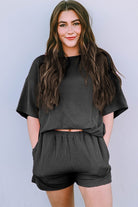 Woman wearing black ribbed textured matching set for women with short sleeves and shorts