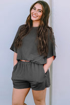 Smiling woman wearing a black ribbed textured matching set for women with short sleeves and shorts