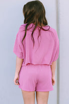 Back view of woman wearing pink ribbed textured matching set for women with shorts and loose top