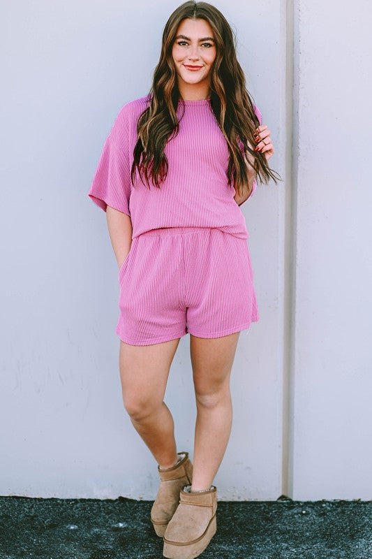 Woman wearing a pink ribbed textured matching set for women with short sleeves and shorts paired with tan ankle boots