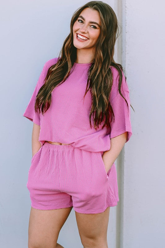 Woman wearing a pink ribbed textured matching set for women consisting of a loose top and shorts