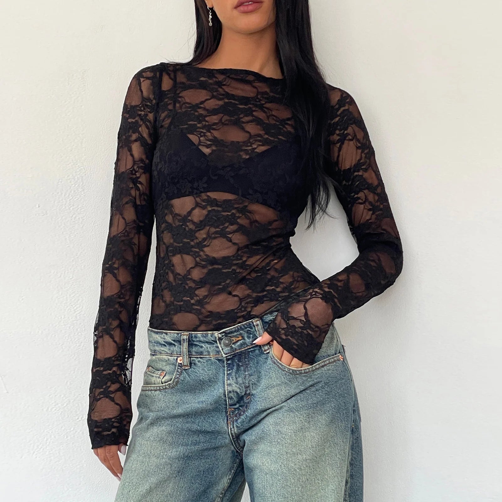 Woman wearing a black sexy lace crop top set with long sleeves paired with blue jeans