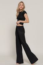 Woman wearing black vacation casual two piece set with short sleeve top and wide leg pants