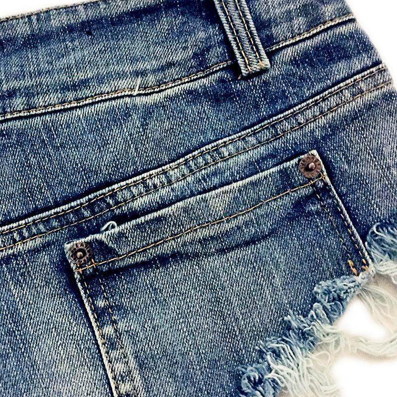 Close-up of vintage blue denim shorts featuring distressed frayed edges and classic back pockets